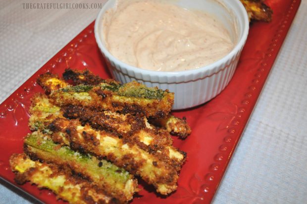 Baked Parmesan Zucchini Fries on red platter, with dipping sauce.