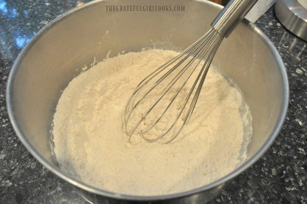 Whisk with flour in metal bowl