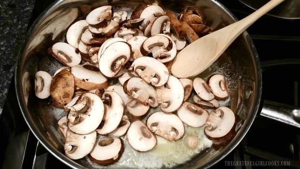 Raw mushrooms cooking in melted butter in silver skillet