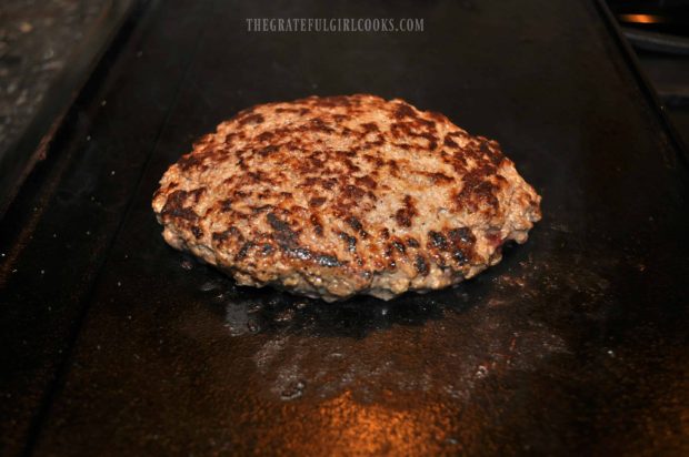 Beef cooking on indoor cast iron grill for a patty melt.