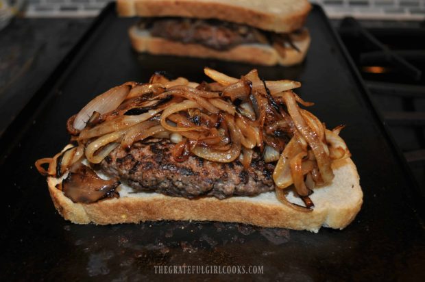 Patty melt is piled high with cooked onion slices.