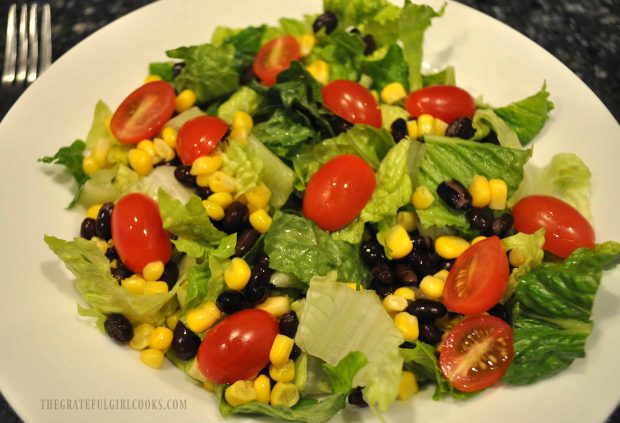 Building the Southwest chicken salad with lettuce, corn, black beans and cherry tomatoes.