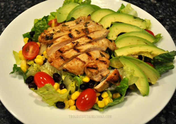 Grilled chicken strips and sliced avocados are added to the salad.