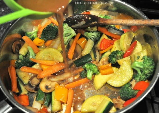 Pouring Asian sauce into veggies in skillet