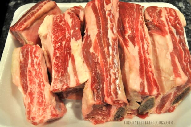 Raw beef short ribs unwrapped on white tray