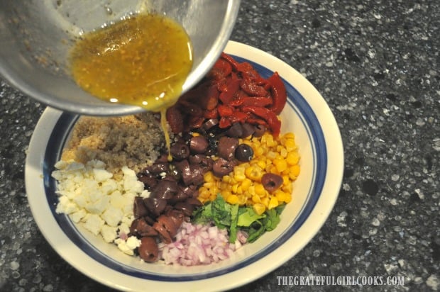 Pouring salad dressing over veggies in salad bowl