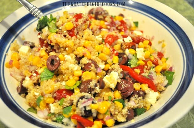 Mixing salad ingredients with a fork in a white bowl