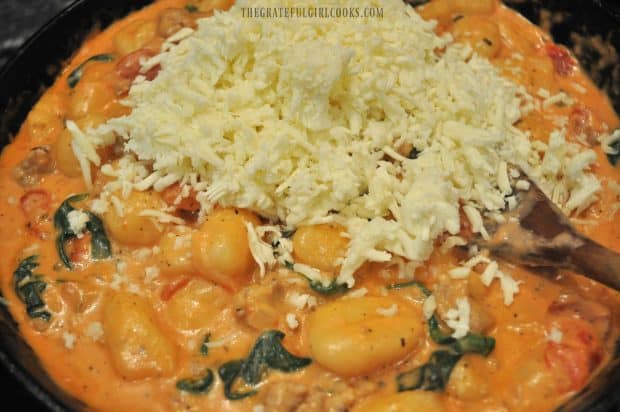 Mozzarella cheese added to skillet with creamy sausage gnocchi