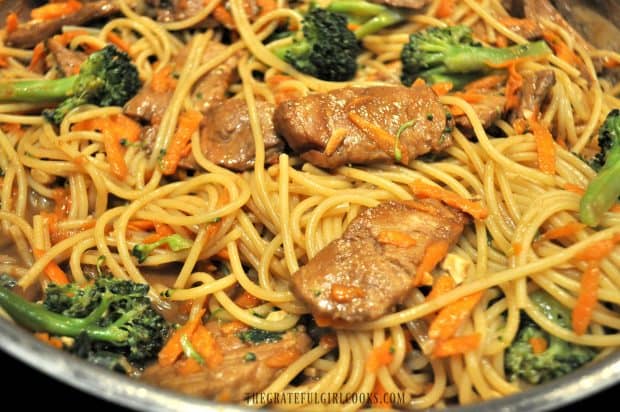 Close up of pork slices, broccoli, carrots and noodles in skillet