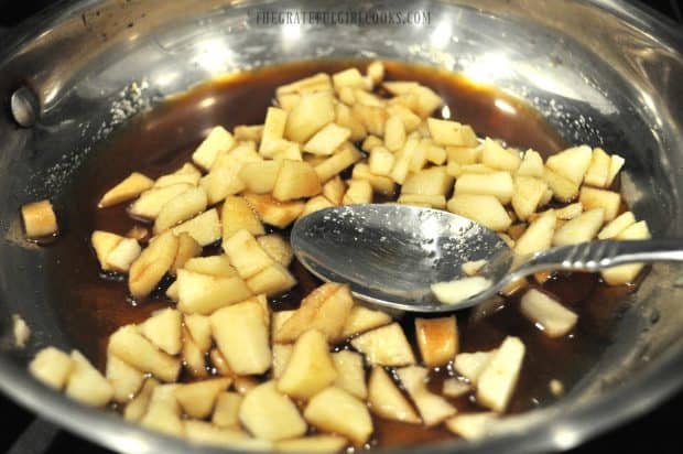 Diced apples cooking with brown sugar, cinnamon and water in skillet