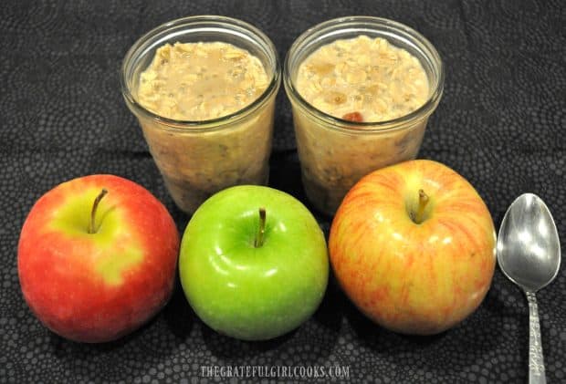 Two jars of overnight oats with a spoon and three apples in front