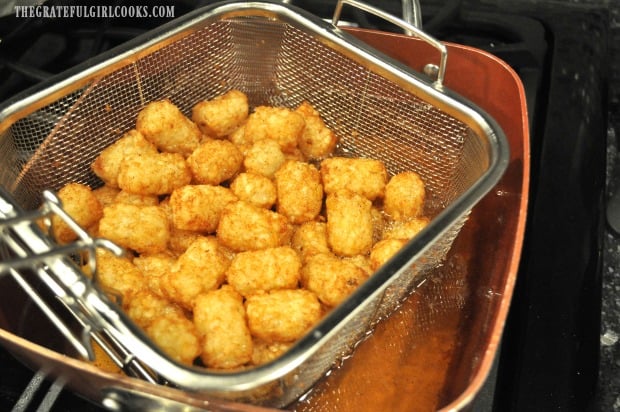 Golden brown tater tots are removed from cooking oil