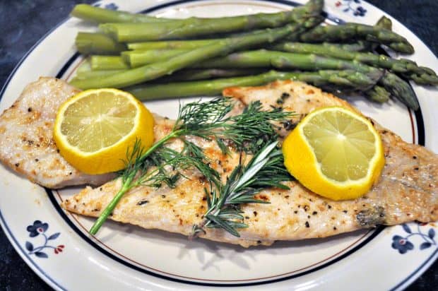 Pan-seared rockfish with lemon and herbs on plate with asparagus