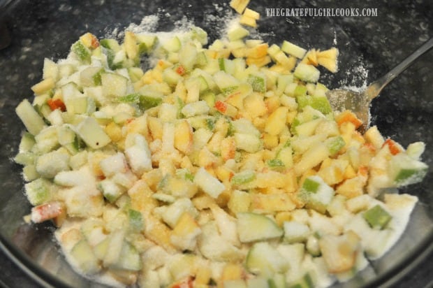 Diced apples for muffins are coated with sugar in bowl