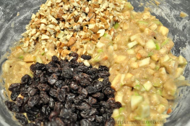 Raisins and pecans are added to apple muffin batter in bowl