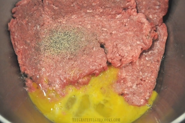 Ground beef, eggs and spices in bowl before mixing