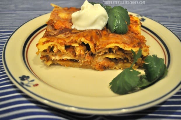 Chicken Enchilada Mole Casserole on a plate, with sour cream and cilantro garnish