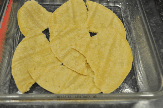 Torn tortillas are layered into casserole dish