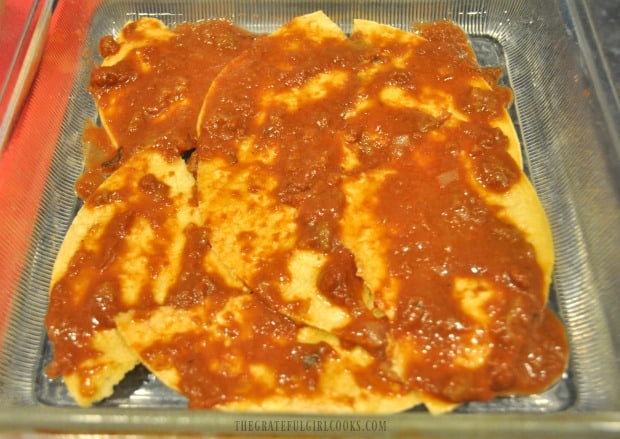 Enchilada/mole sauce is spread over tortillas