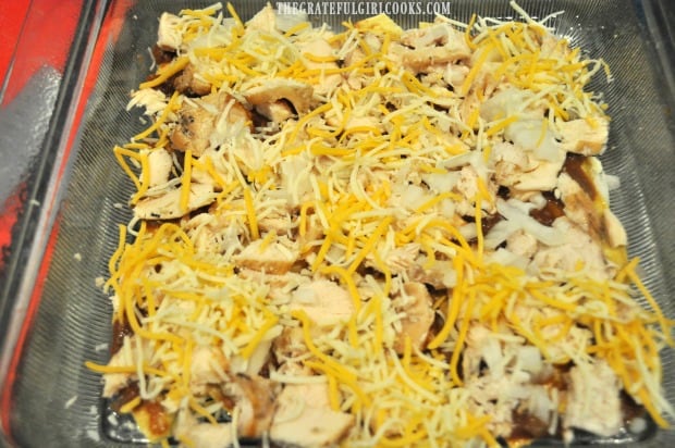 Chicken, onions and cheese layered onto enchilada casserole