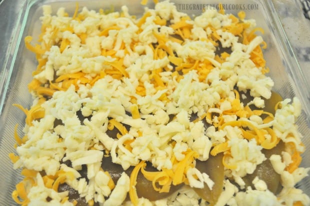 Grated jack and cheddar cheese on top of green chiles in glass baking dish