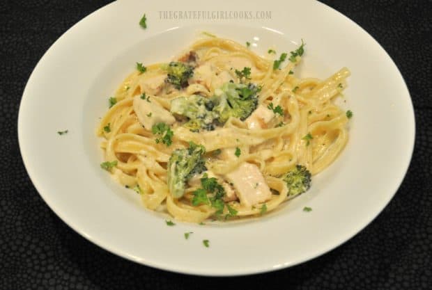 Chicken fettucine is garnished with parsley before serving