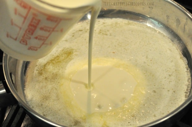 Heavy whipping cream is added to alfredo sauce in pan