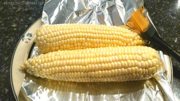 Corn is lightly brushed with oil before grilling