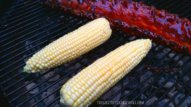 Corn is placed on hot BBQ grill to cook