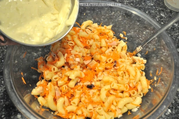 Salad dressing is poured over pasta salad with tuna