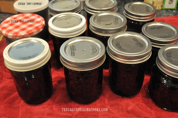 Jars of jam cooling down on dish towel on counter.