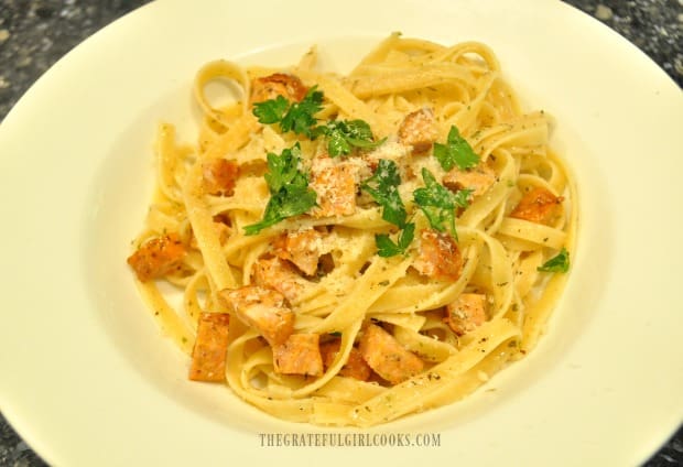 Chicken sausage pasta is garnished with parsley and Parmesan cheese.