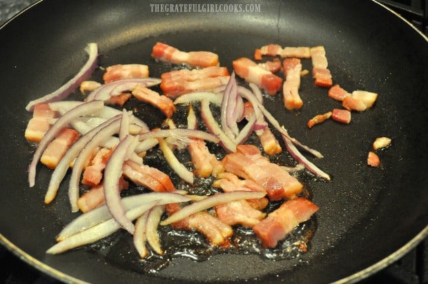 Bacon pieces and red onion slices sauté in skillet