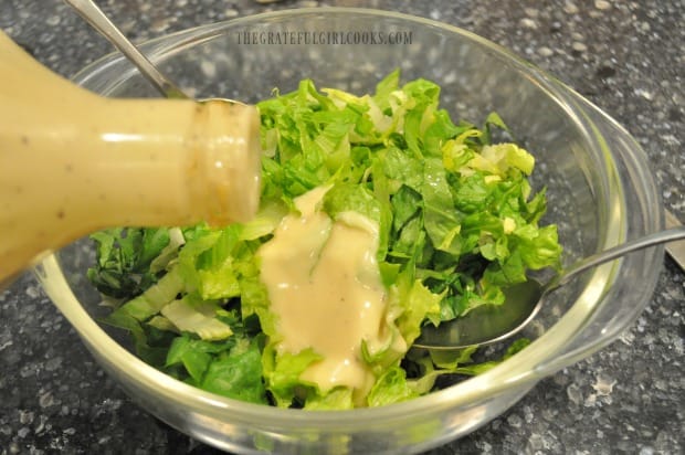 Romaine lettuce is topped with Caesar dressing.
