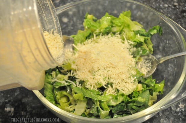 Shredded Parmesan cheese is added to caesar salad.