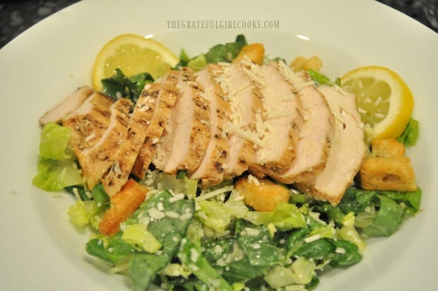 Grilled chicken breast is sliced, then fanned out on top of caesar salad before serving.