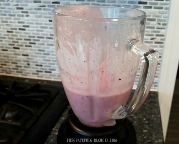 Fruit smoothie is made with ingredients blended in blender.