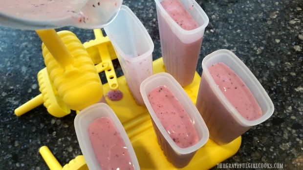 Popsicle molds are filled with fruit smoothie mix.