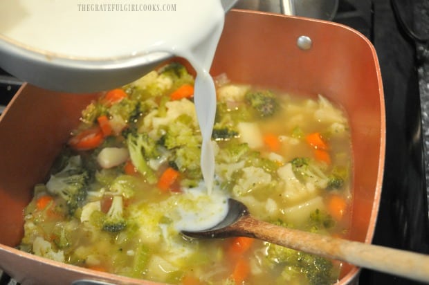 Adding flour slurry to soup to thicken it for vegetable chowder.