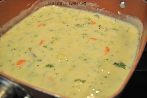 Cheese is mixed into the vegetable chowder until it has melted.