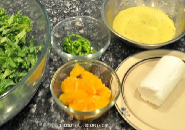 Kale, jalapenos, orange chunks, goat cheese and salad dressing ready to make a kale orange salad.