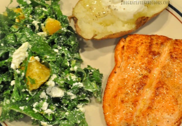 Baked potato and roasted salmon on dinner plate with the kale orange salad.