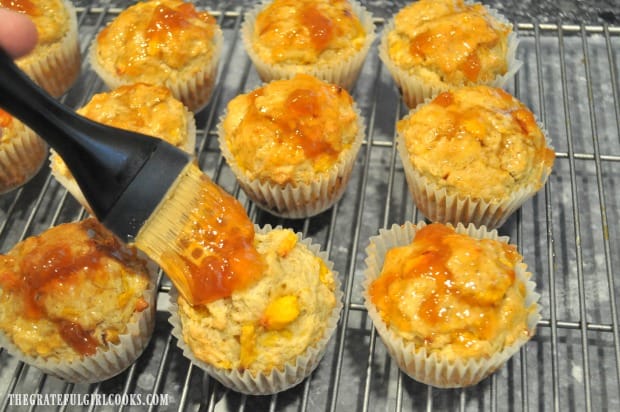 Peach jam is brushed on top of each muffin with a pastry brush.