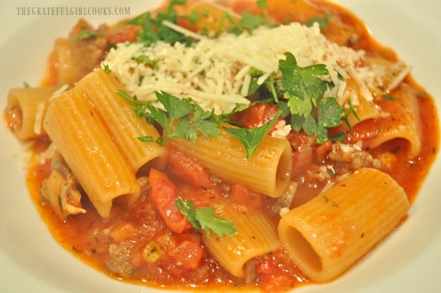 Rigatoni sausage mushroom ragu is garnished with flat leaf parsley and Parmesan cheese.