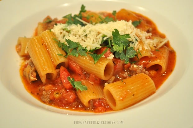 Rigatoni sausage mushroom ragu is served, garnished with Parmesan cheese and parsley.