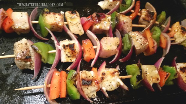 Swordfish kabobs are turned as they cook on griddle.