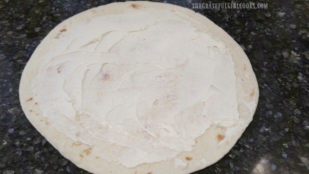 Flour tortilla is spread with cream cheese and ranch dressing to make rollups.