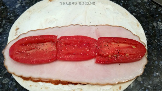 Turkey slices and sliced roma tomatoes are place on flour tortilla for rollups.