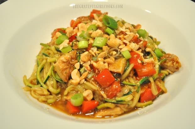 Bowl of Kung Pao Zoodles garnished with chopped peanuts and green onions.