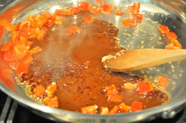 Asian sauce and red bell peppers are added to skillet for kung pao sauce.